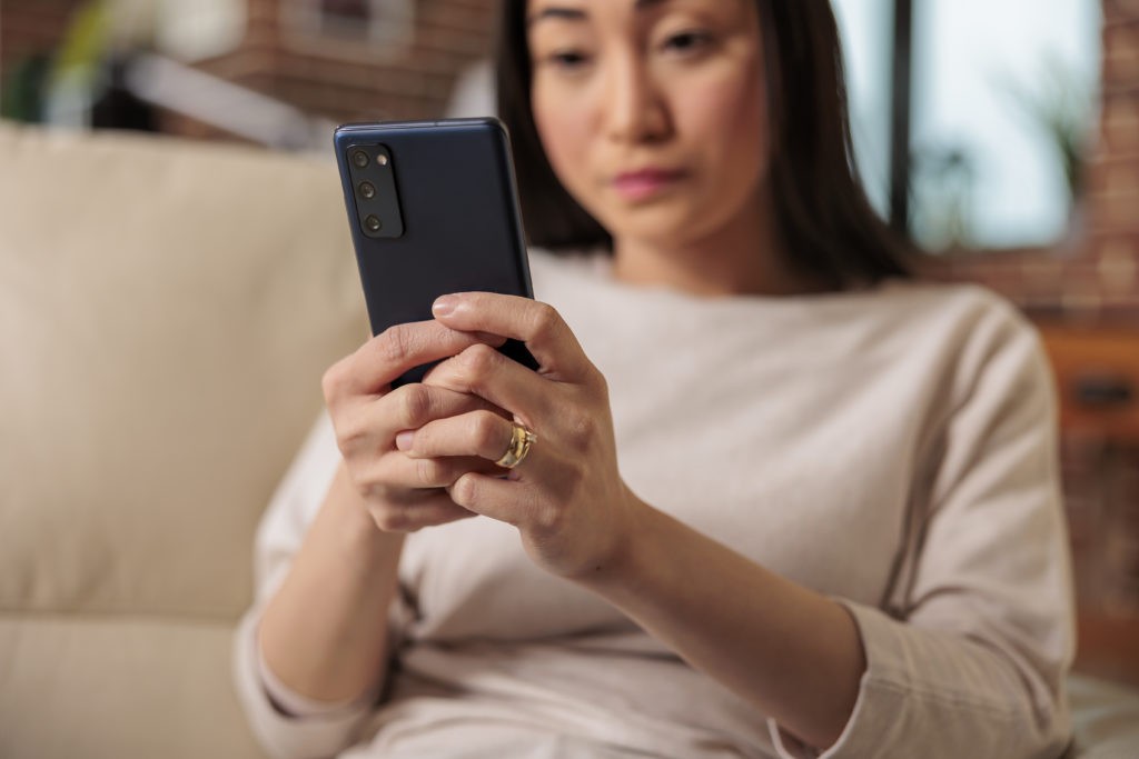 Mulher oriental, cabelo preto liso com suéter e celular na mão, para onde olha 

O que faz um Social Media