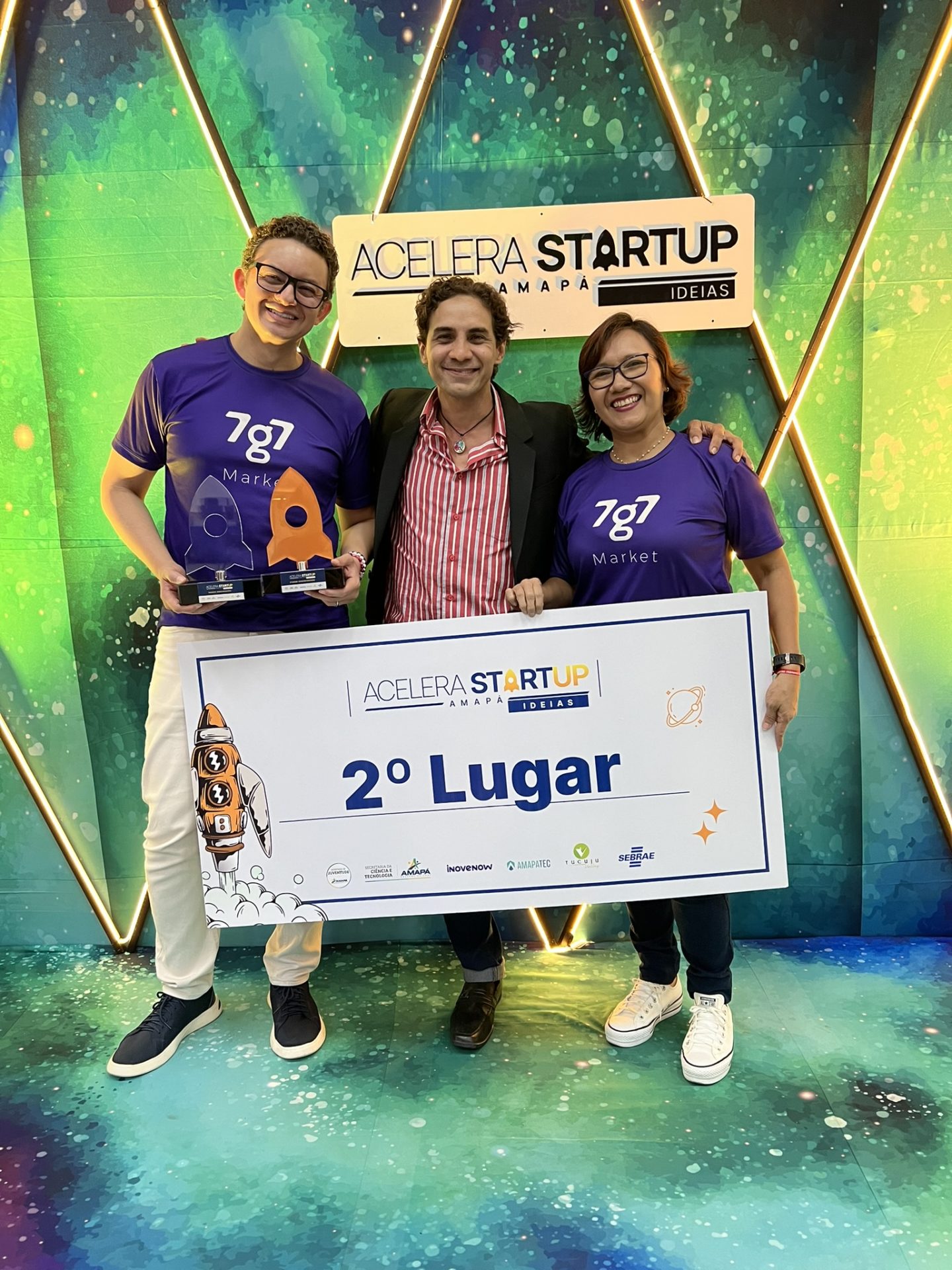 Três participantes posam com troféus e a placa de segundo lugar no Demo Day 2023.