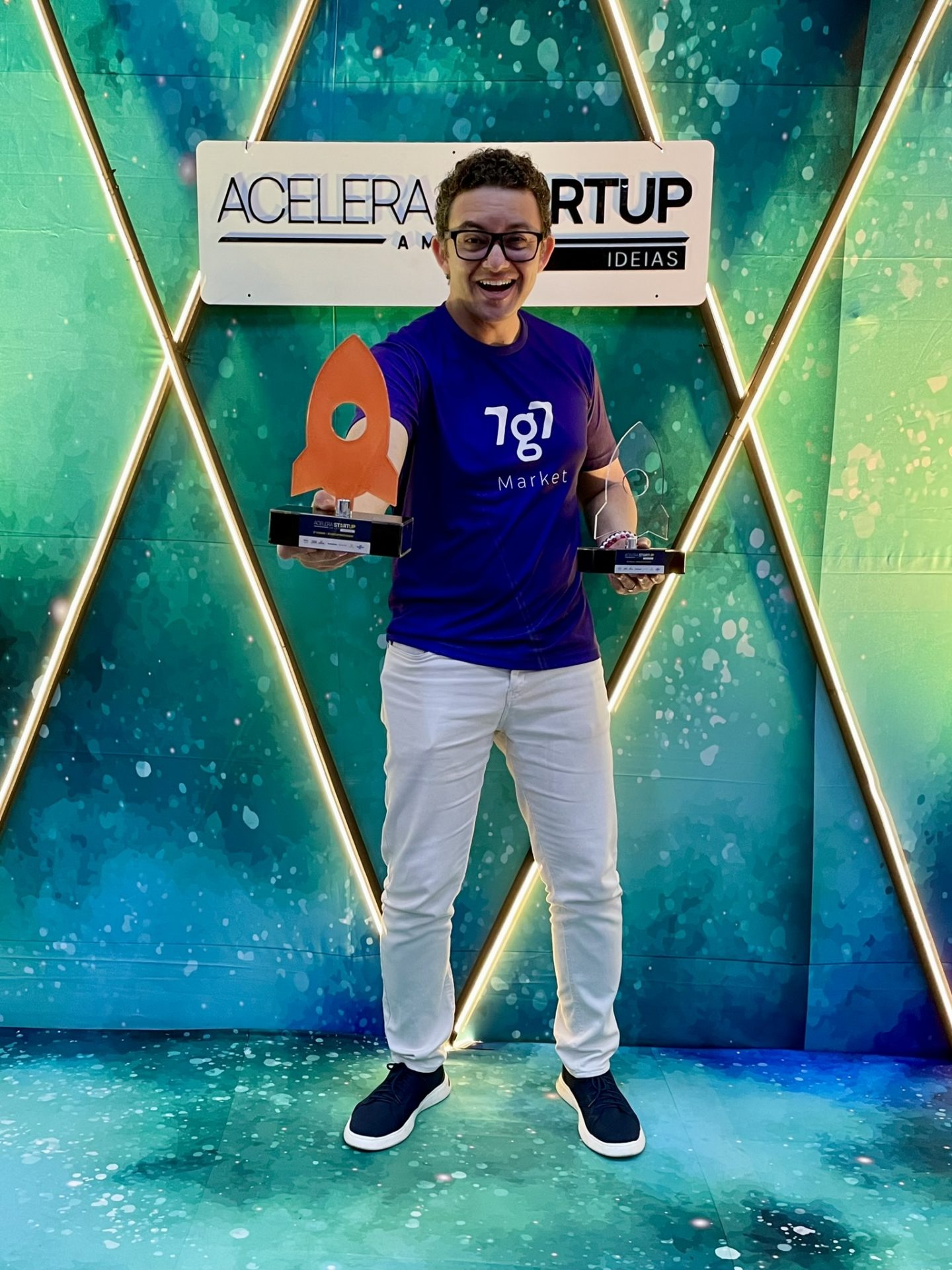 Maikon Richardson segura dois troféus diante do painel Acelera Startup Amapá, em 2023.